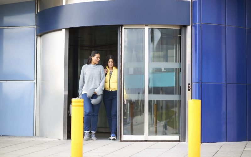 Women exiting revolving door of airport terminal